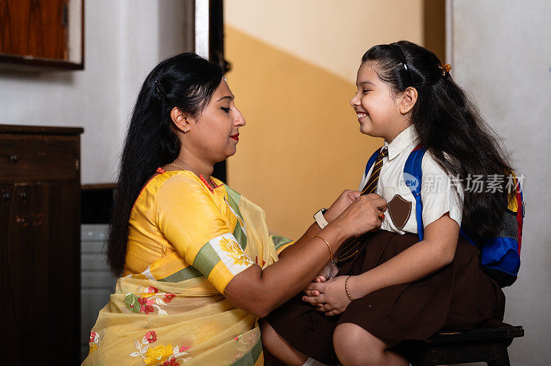 亚洲/印度母亲帮女儿打扮去上学。
